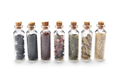 Photo of Row of small glass bottles with different spices on white background