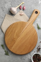 Photo of Cutting board, garlic, spices and rosemary on grey textured table, flat lay. Space for text