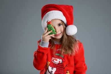 Photo of Cute little girl with Christmas gingerbread cookie on grey background