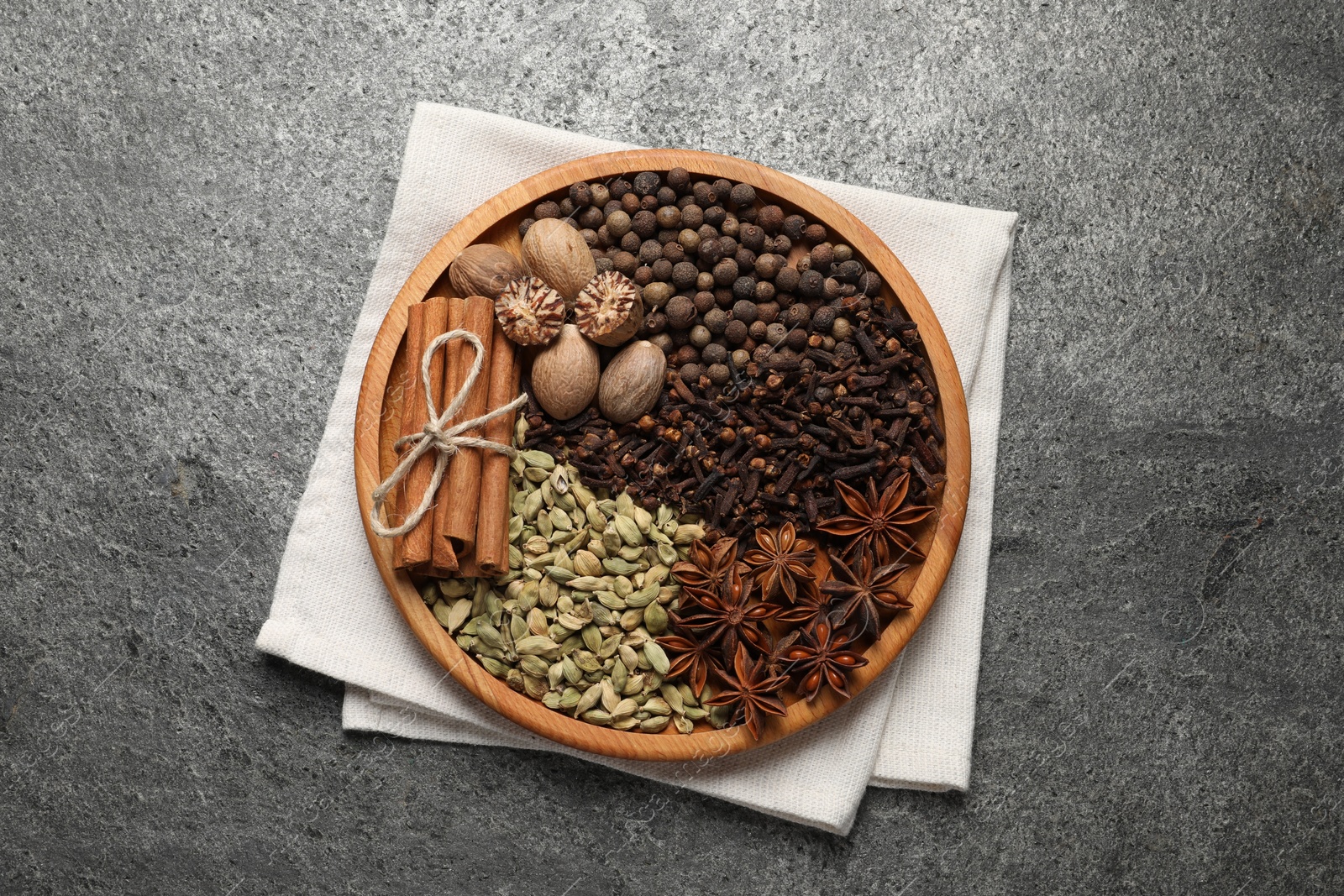 Photo of Different spices and nuts on gray textured table, top view