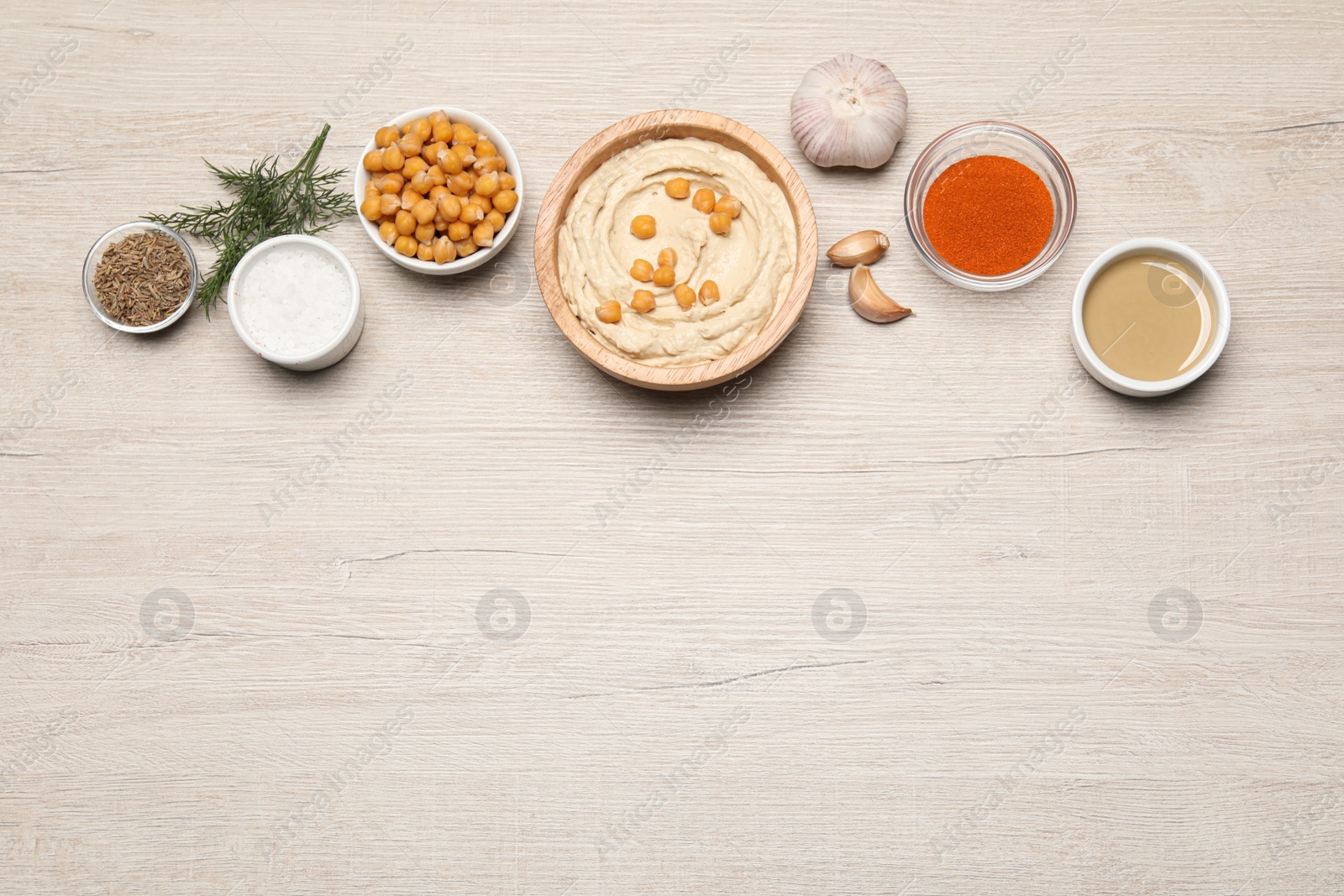 Photo of Bowl with delicious hummus and different ingredients on white wooden table, flat lay. Space for text