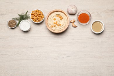 Photo of Bowl with delicious hummus and different ingredients on white wooden table, flat lay. Space for text