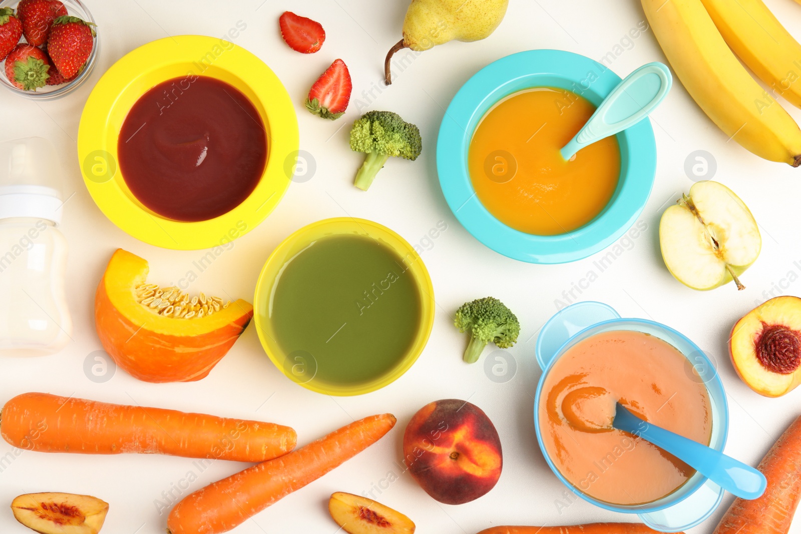 Photo of Baby food in bowls and fresh ingredients on white table, flat lay