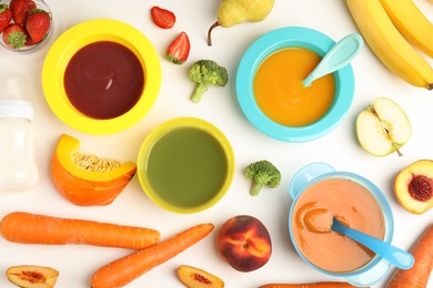 Baby food in bowls and fresh ingredients on white table, flat lay