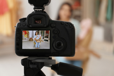 Photo of Fashion blogger recording new video in room, focus on camera