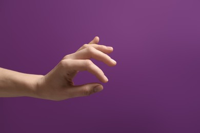 Photo of Woman holding something in hand on purple background, closeup. Space for text