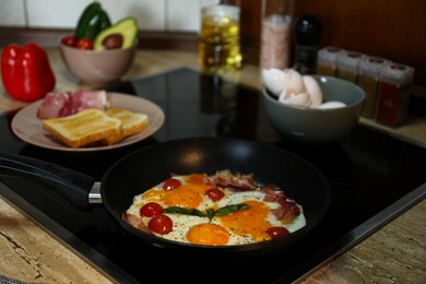 Photo of Tasty eggs with tomatoes and bacon in frying pan for breakfast