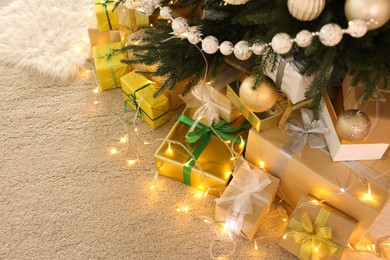 Photo of Decorated Christmas tree, beautiful gift boxes and festive lights indoors