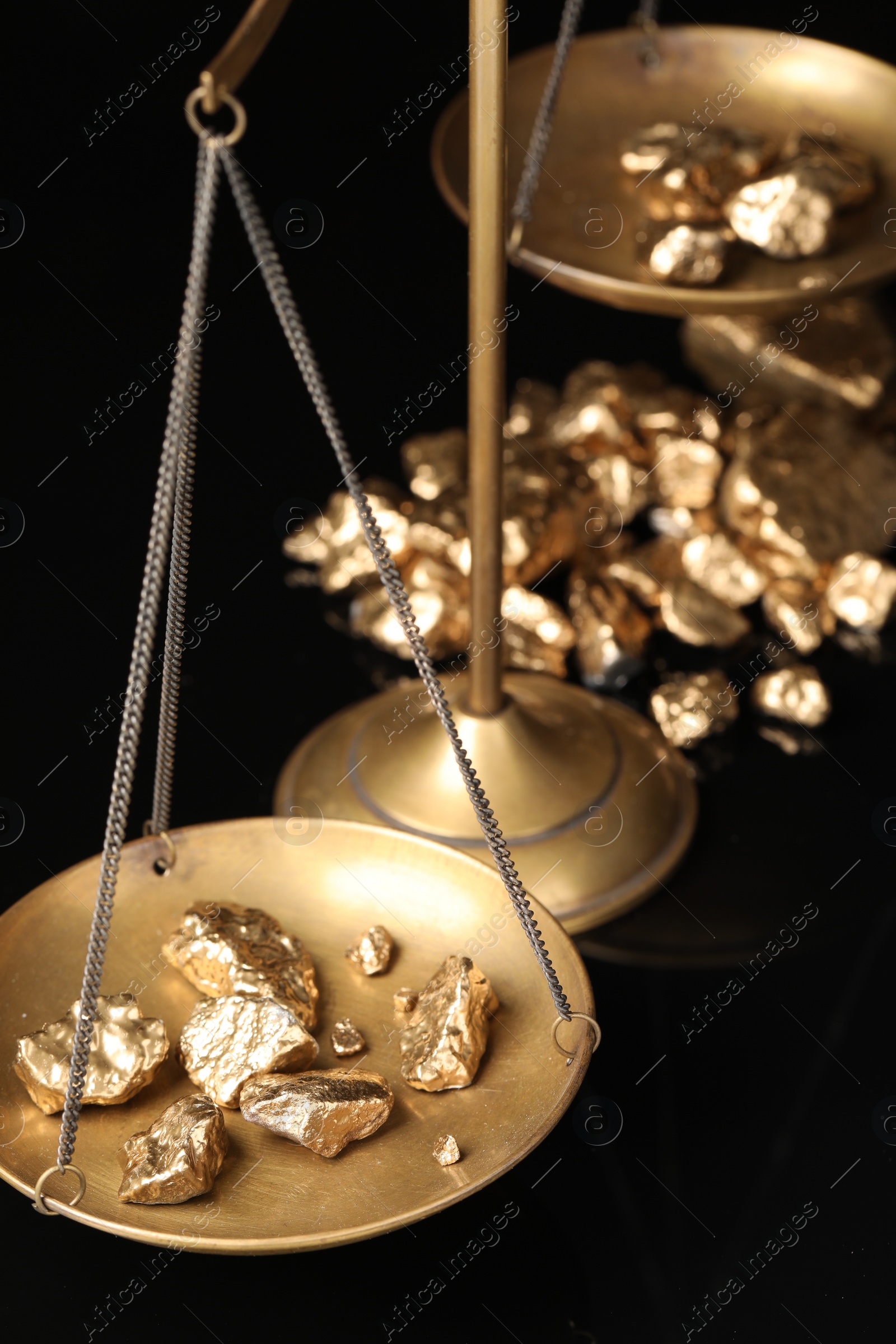 Photo of Vintage scales with gold nuggets on black background