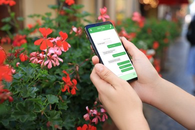 Image of Woman texting via mobile phone outdoors, closeup. Device screen with messages