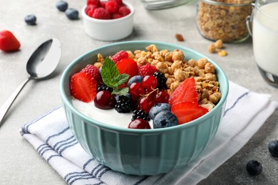 Photo of Bowl with tasty granola and berries on light grey table. Healthy meal