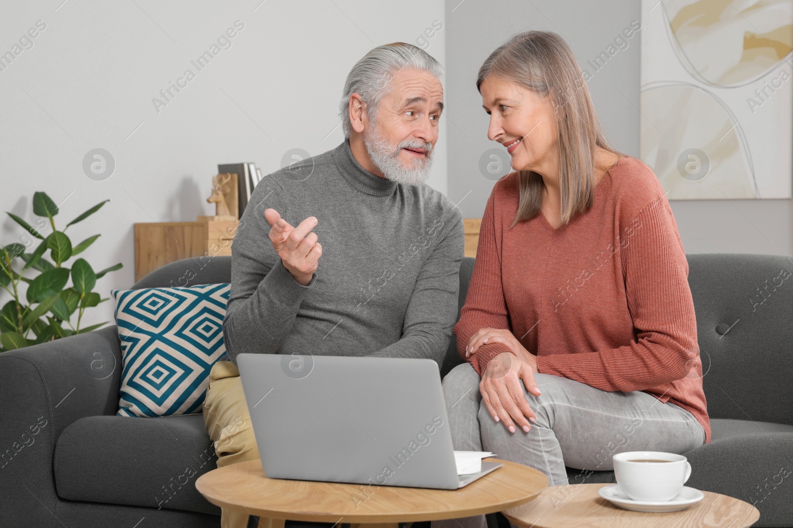 Photo of Elderly couple with laptop discussing pension plan in room