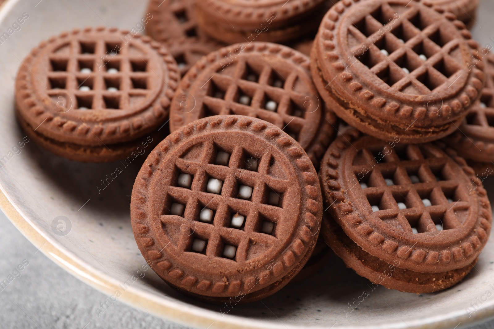 Photo of Tasty chocolate sandwich cookies with cream in bowl, closeup