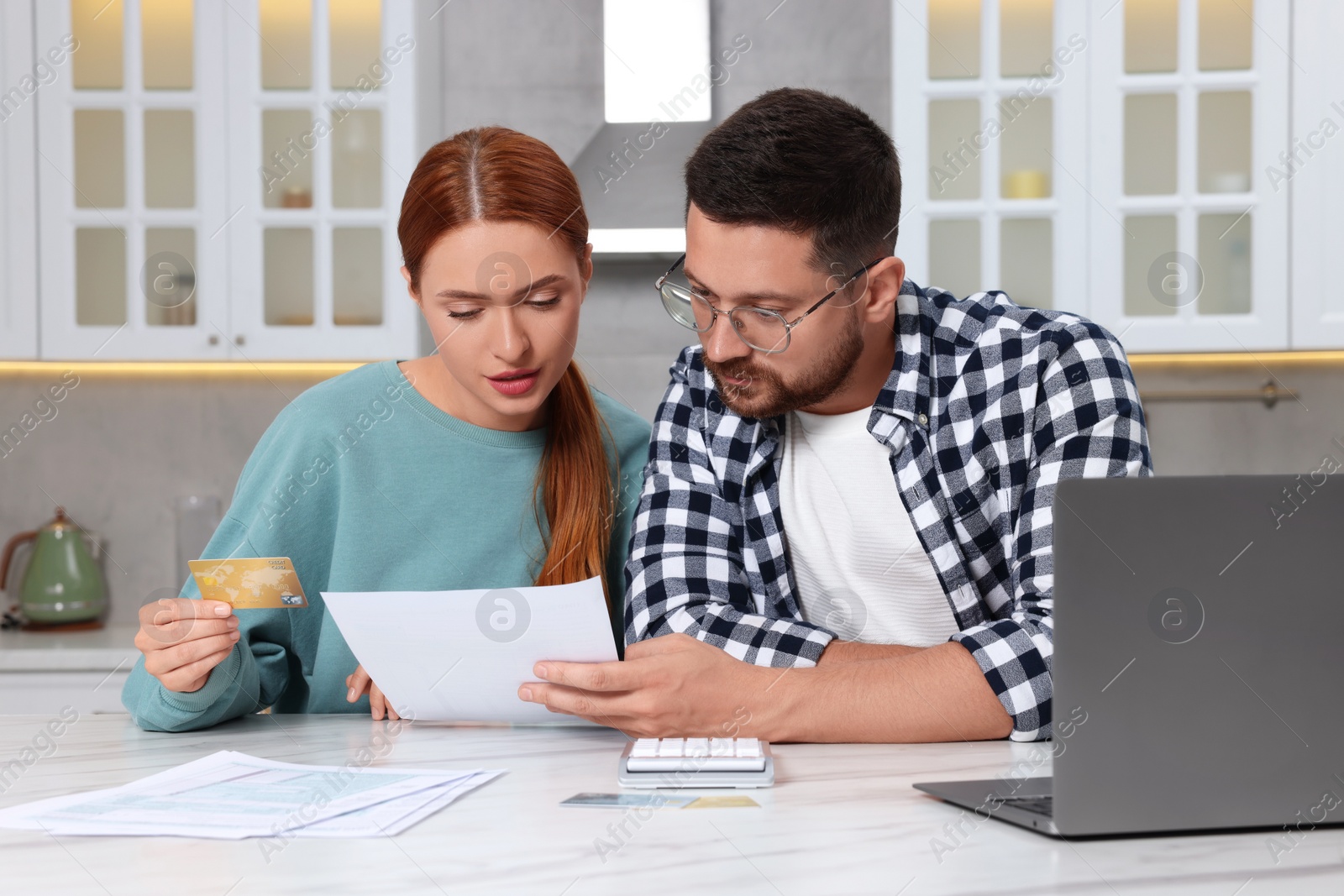 Photo of Couple with credit card using laptop for paying taxes online at home