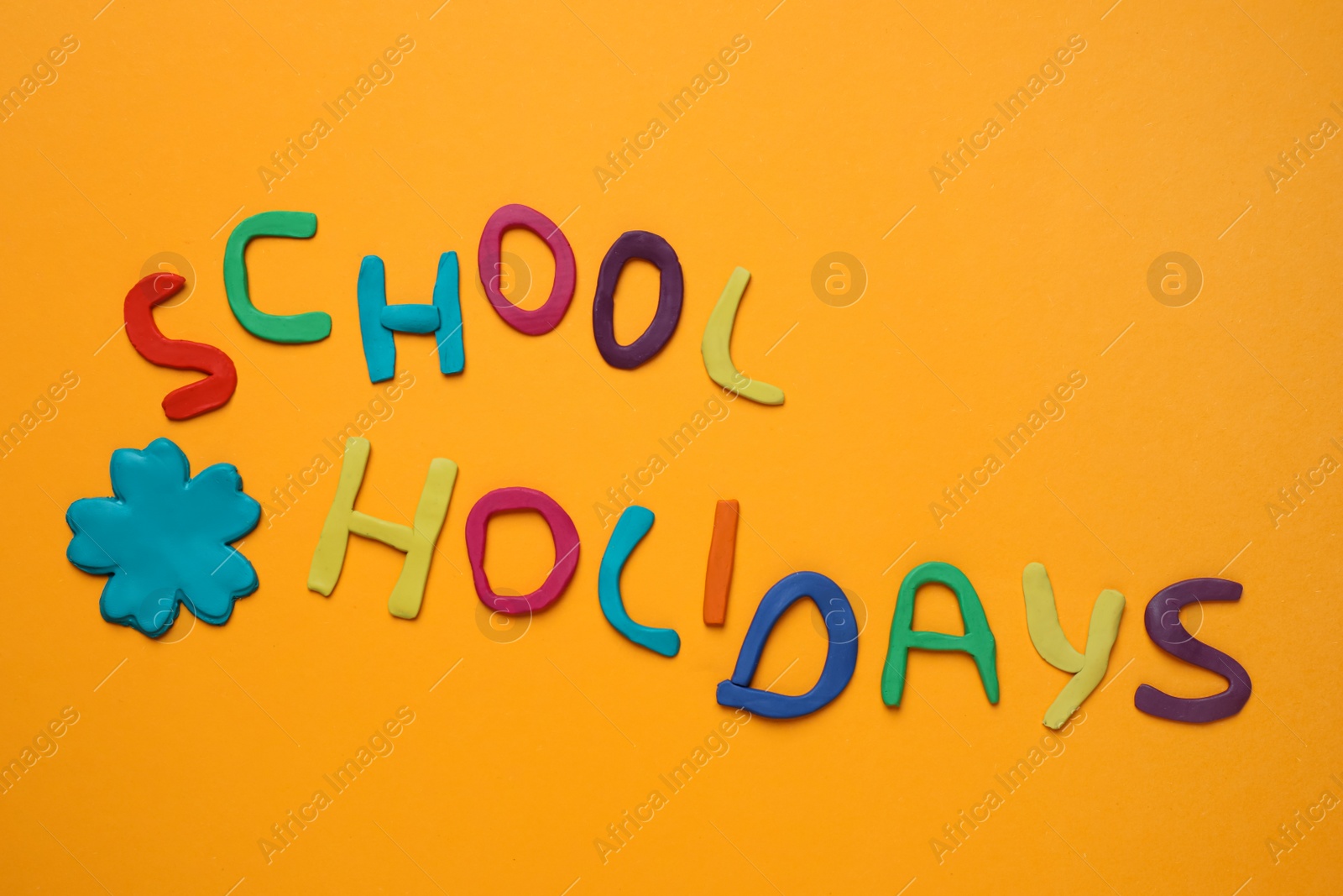 Photo of Phrase School Holidays made of modeling clay on orange background, top view