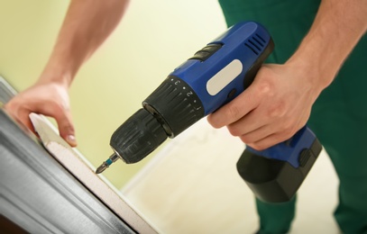 Photo of Worker installing drywall indoors, closeup. Home repair service