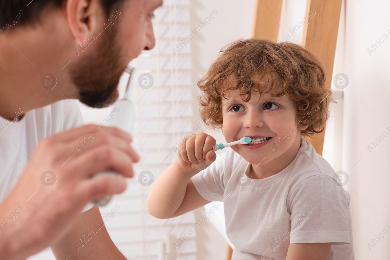 Photo of Father and his son brushing teeth together in bathroom