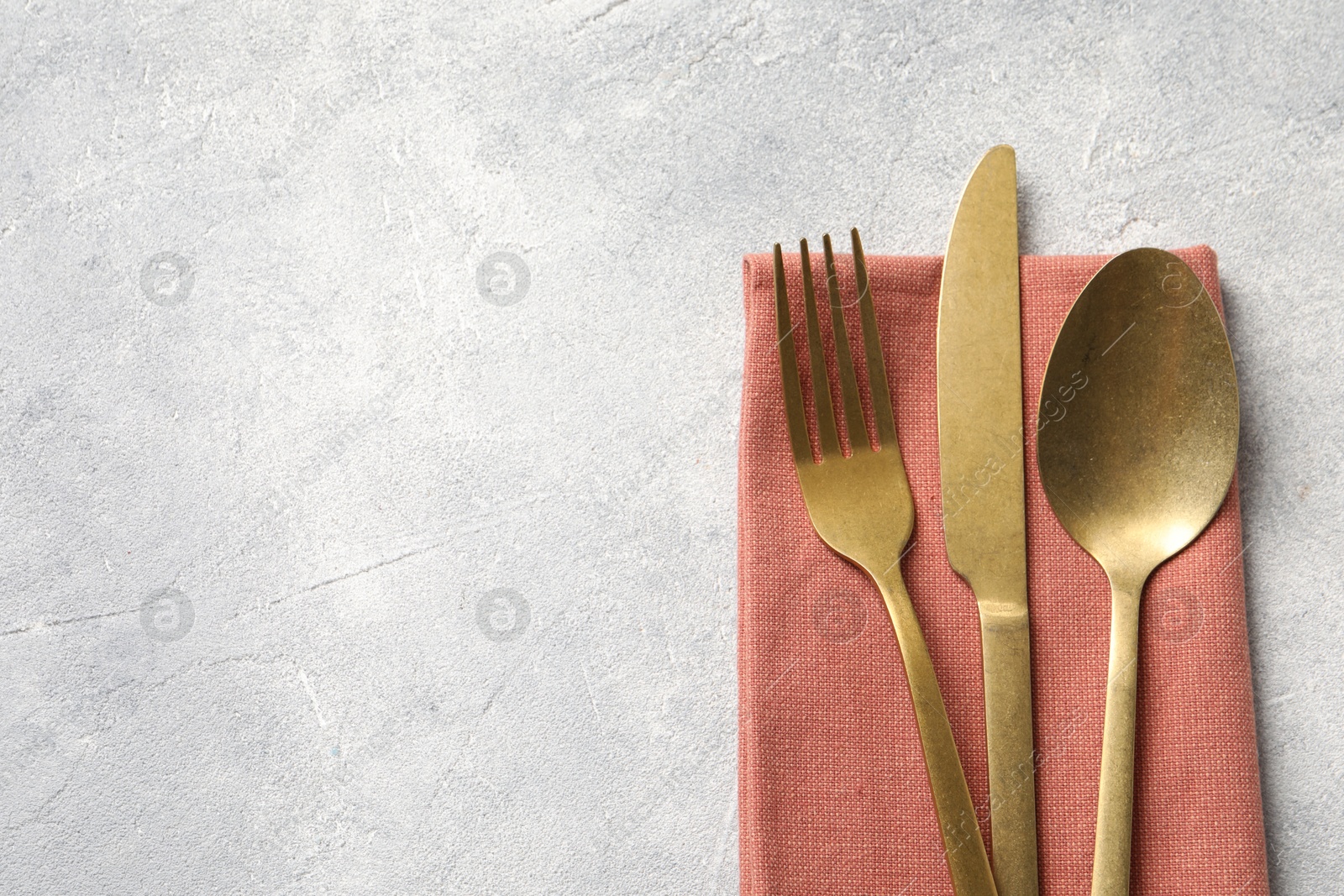 Photo of Stylish cutlery and napkin on light grey table, top view. Space for text