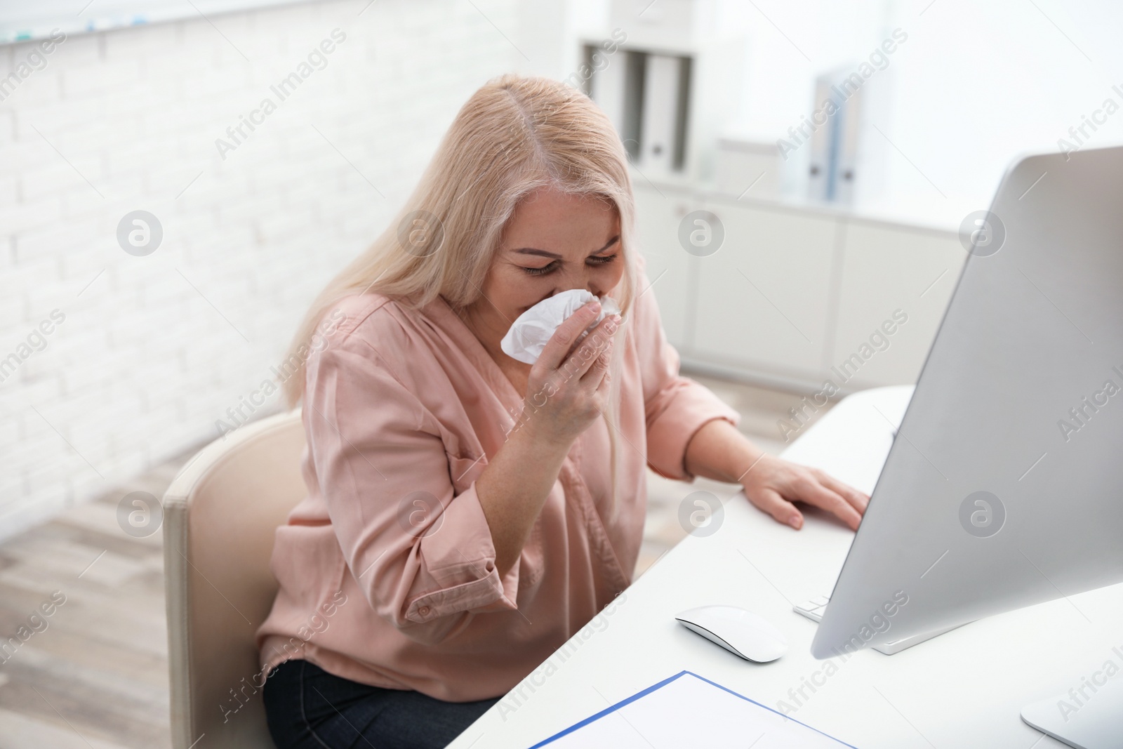 Photo of Sick mature woman at workplace. Dangerous virus