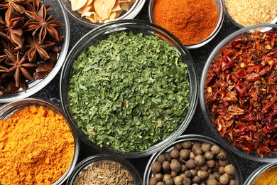 Glass bowls with different spices on grey textured table, flat lay