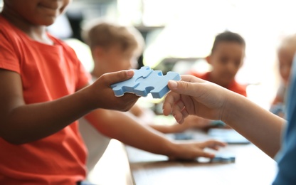 Photo of Little children playing with puzzle indoors, focus on hands. Unity concept