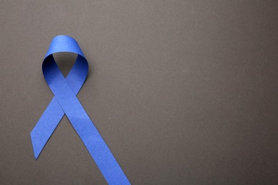 Photo of Blue ribbon on grey background, top view with space for text. Symbol of social and medical issues