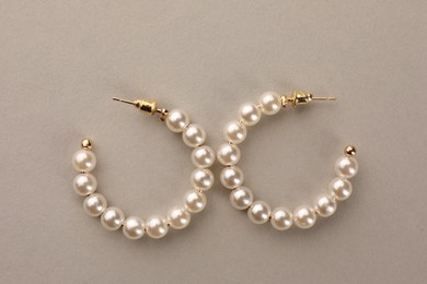 Elegant earrings with pearls on beige background, top view