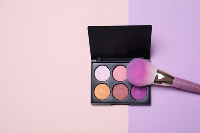 Photo of Eyeshadow palette and makeup brush on color background, flat lay with space for text