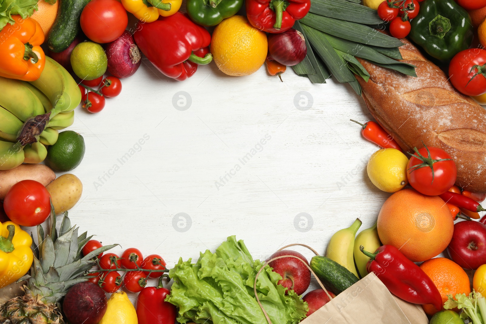 Photo of Frame of paper bag with fresh vegetables and fruits on white wooden background, top view. Space for text