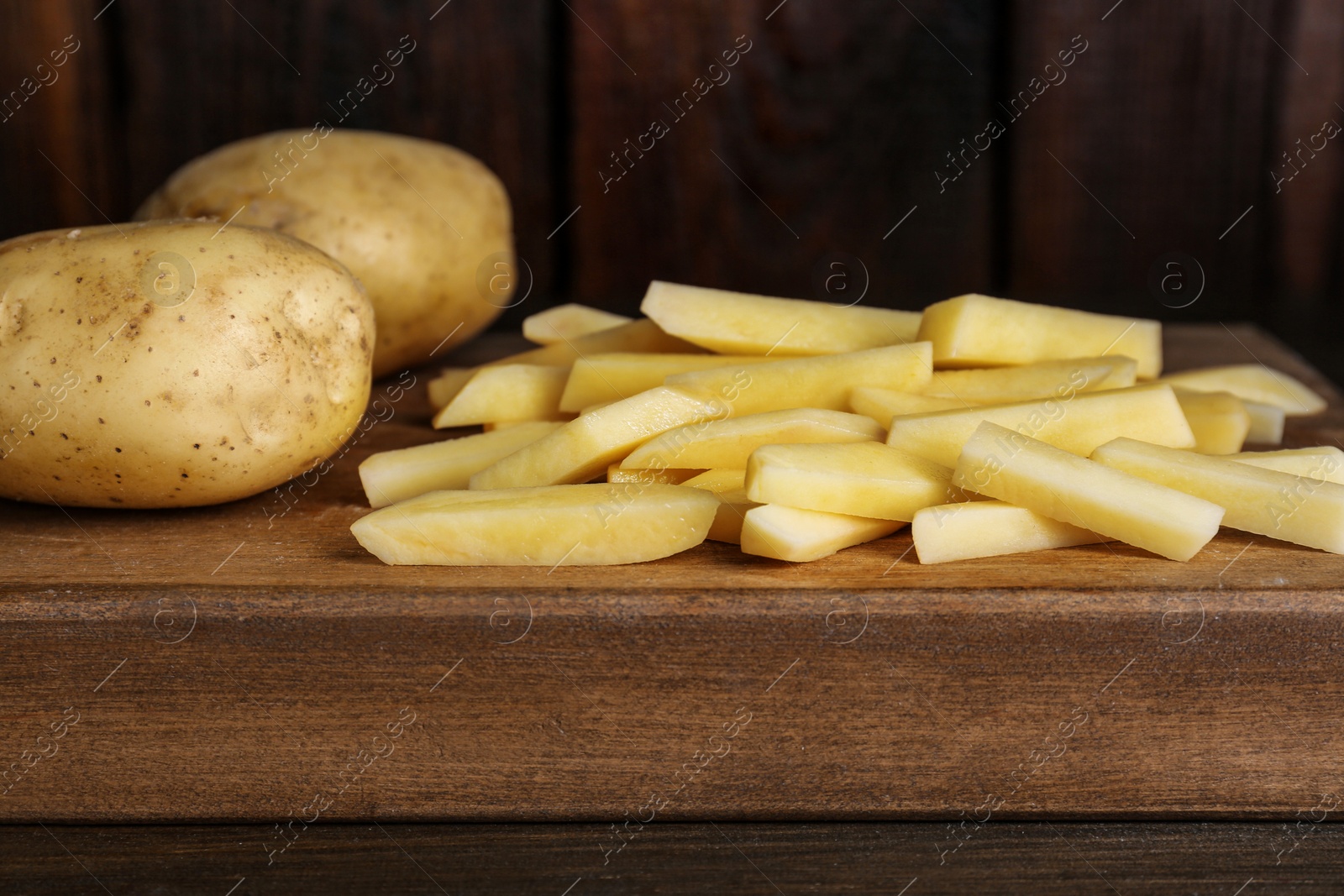 Photo of Whole and cut raw potatoes on wooden table