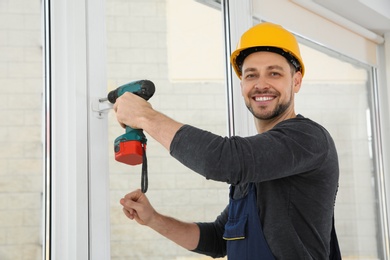 Construction worker using drill while installing window indoors