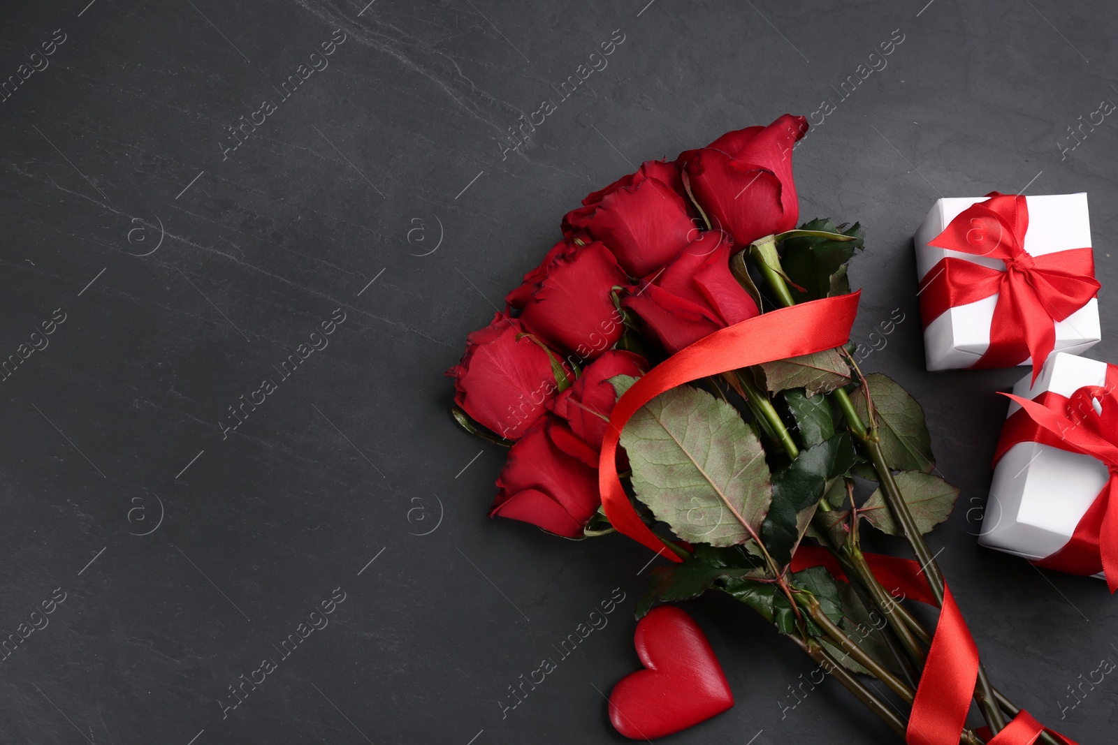 Photo of Flat lay composition with beautiful red roses and gift boxes on black background, space for text. Valentine's Day celebration