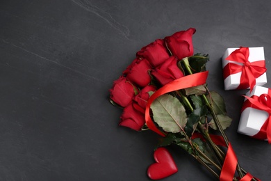 Flat lay composition with beautiful red roses and gift boxes on black background, space for text. Valentine's Day celebration