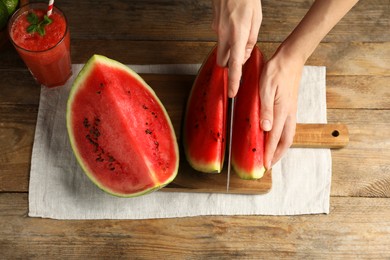 Photo of Woman cutting delicious watermelon at wooden table, above view