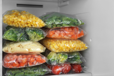 Plastic bags with different frozen vegetables in refrigerator