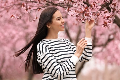 Photo of Pretty young woman near blooming tree in park. Spring look