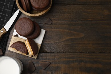 Photo of Tasty choco pies, pieces of chocolate and knife on wooden table, flat lay. Space for text
