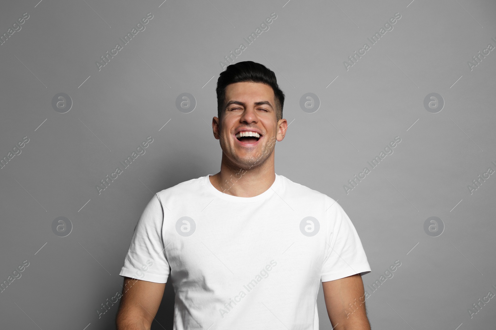 Photo of Handsome man laughing on grey background. Funny joke