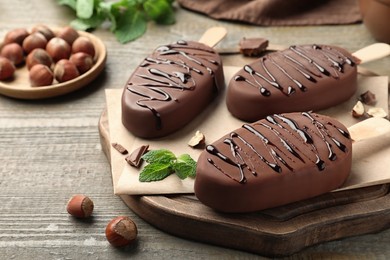 Delicious glazed ice cream bars, nuts and mint on wooden table