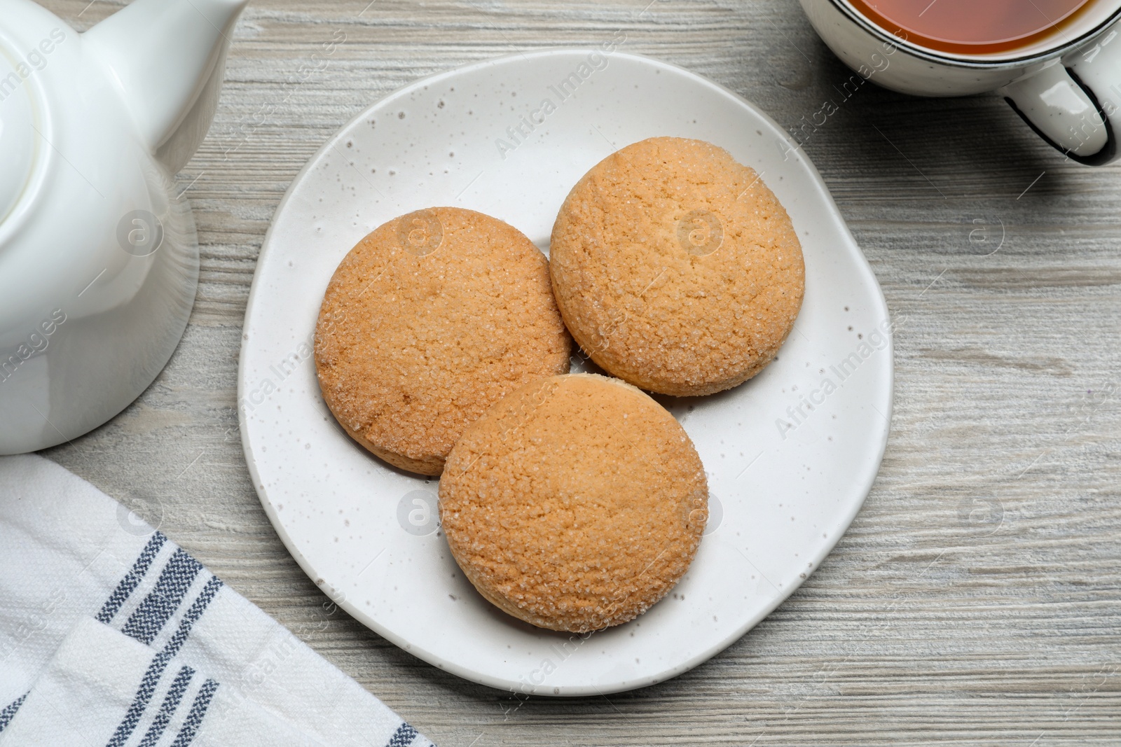 Photo of Delicious sugar cookies and cup of tea on white wooden table, flat lay