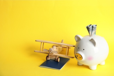 Photo of Piggy bank with toy airplane and passport on color background, space for text. Travel agency