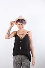 Trendy young woman with tattoos on white background