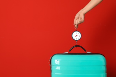 Woman weighing suitcase against color background, closeup. Space for text