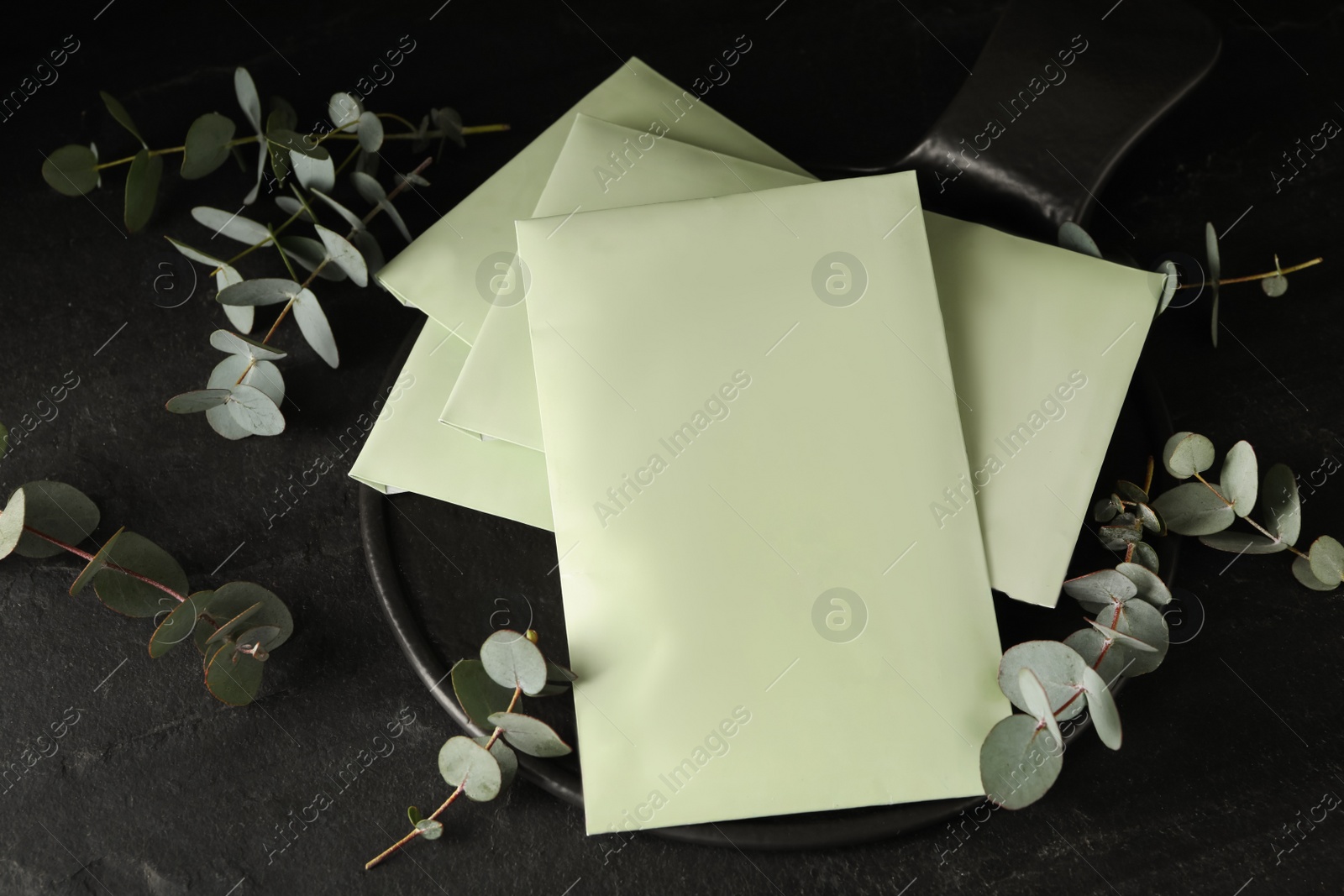 Photo of Scented sachets and eucalyptus branches on black table