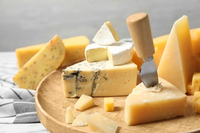 Photo of Different types of delicious cheese in wooden plate, closeup