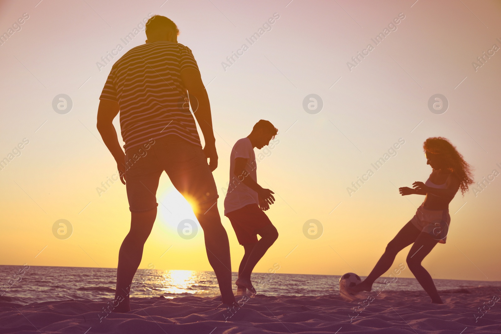 Photo of Friends playing football on beach at sunset