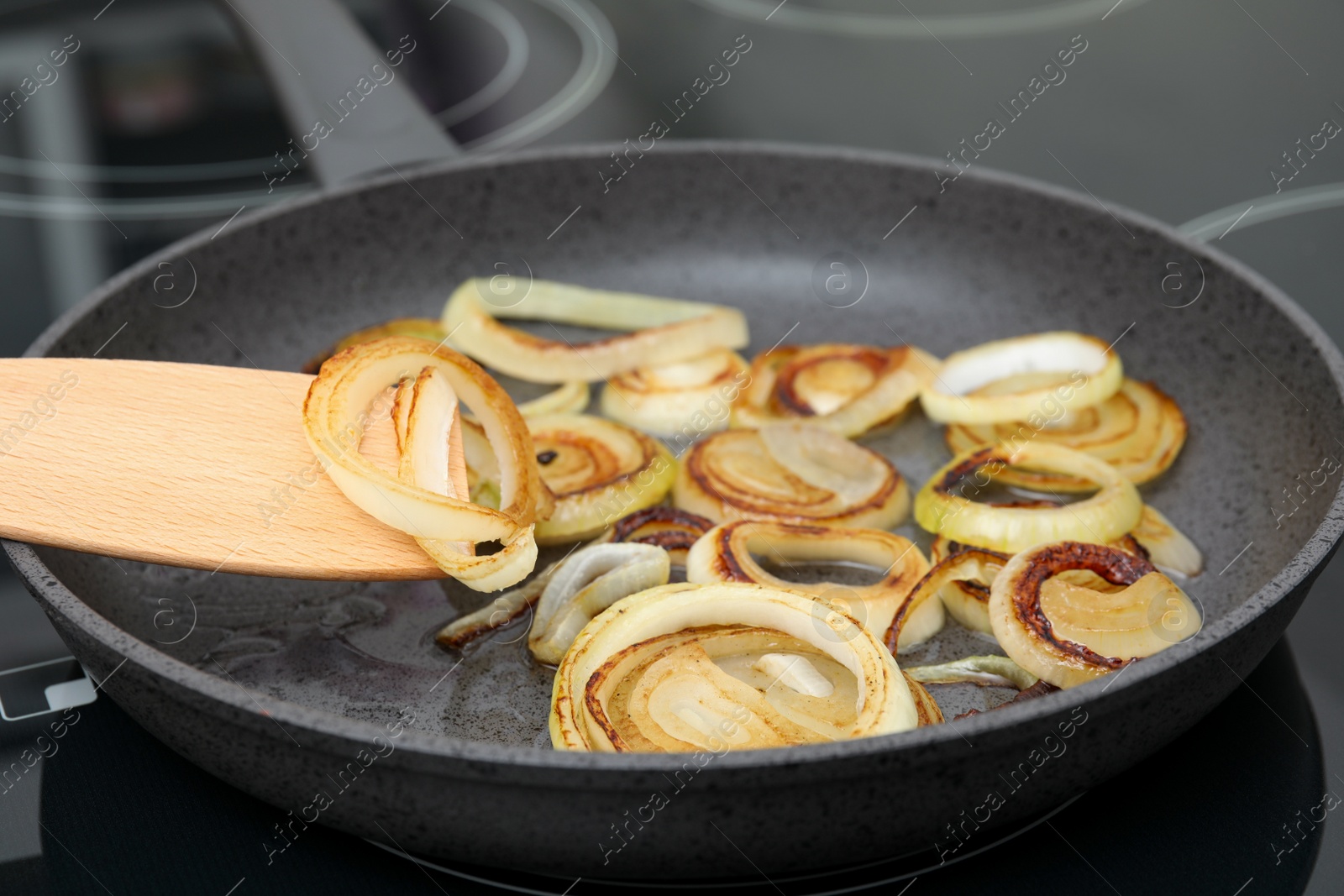 Photo of Cooking onion rings in frying pan, closeup