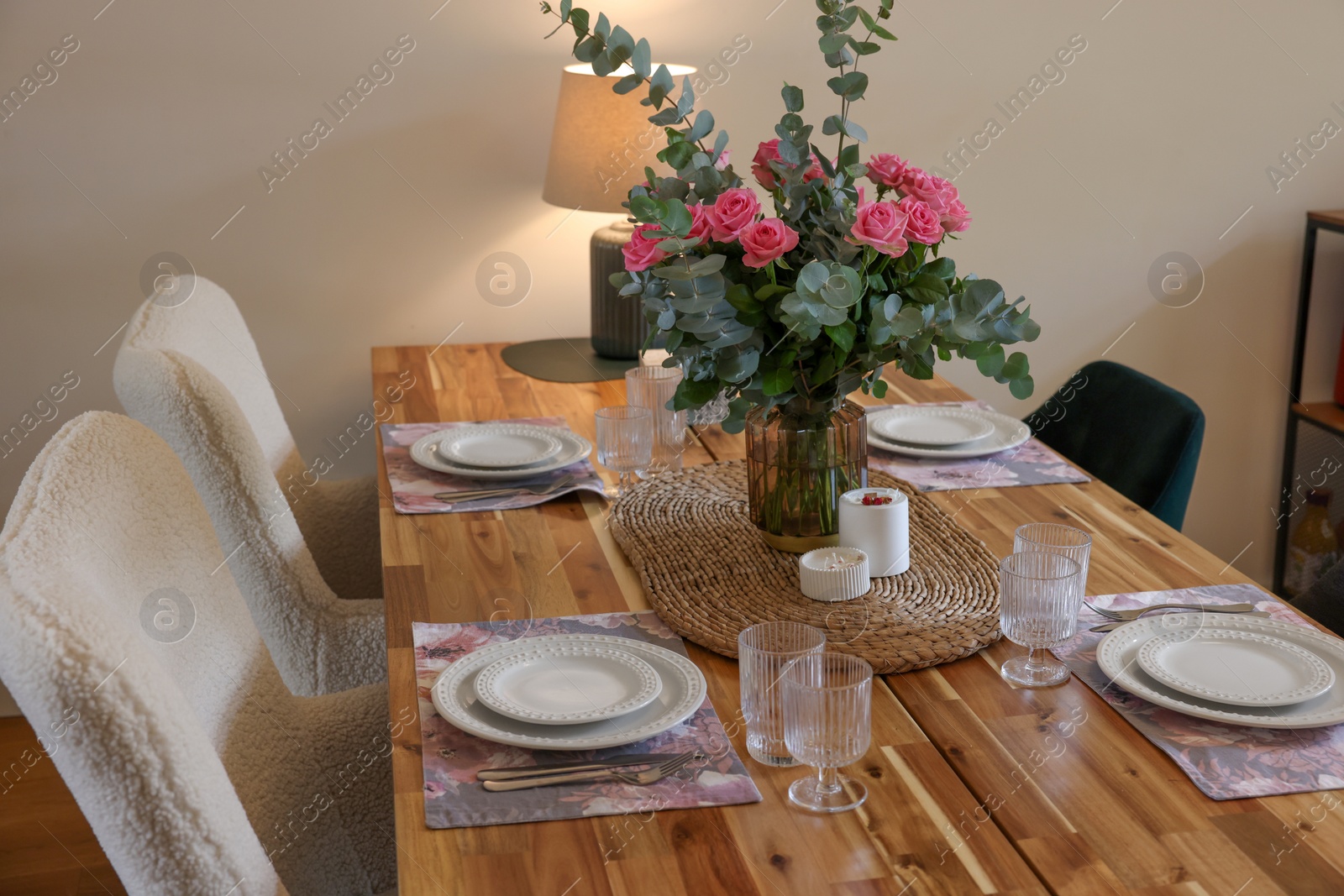 Photo of Beautiful table setting with bouquet and candles indoors. Roses and eucalyptus branches in vase