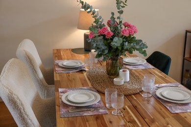 Beautiful table setting with bouquet and candles indoors. Roses and eucalyptus branches in vase