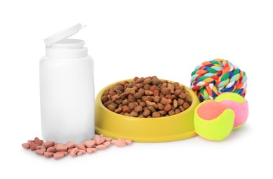 Photo of Dry pet food in bowl, vitamins and toys isolated on white